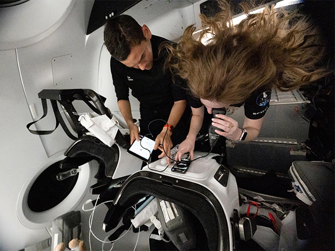 Two people in zero-gravity monitor scientific equipment