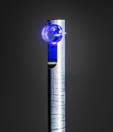 A crystal of calcium fluoride that is lit by blue light and mounted on a post